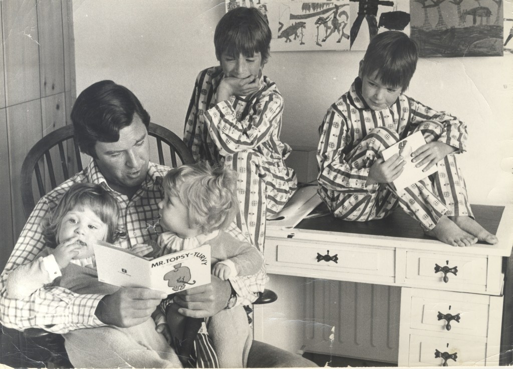 Black and white photo of author Roger Hargreaves reading book Mr. Topsy-Turvy to his four children